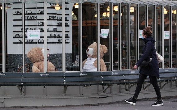一名女子走過法國巴黎街頭一家關門的餐館。（圖源：新華社）