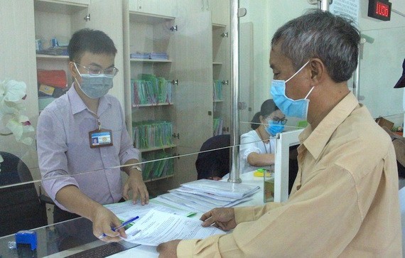 一名平新郡公務員在為當地居民解決行政手續。(圖源:黎叉)