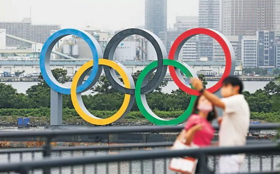 民眾與豎立在東京台場區域的奧運五環標誌合影。(圖源:新華社)