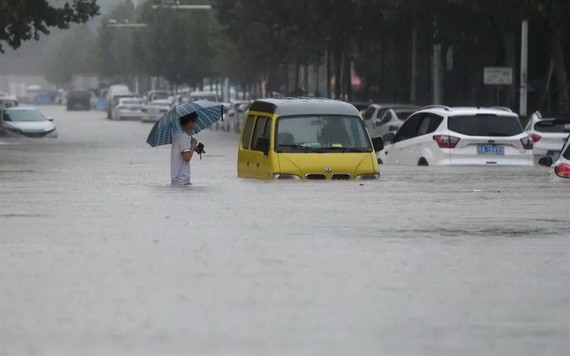 中國河南鄭州強降雨,行人20日涉水通過積水路段。(圖源:互聯網)
