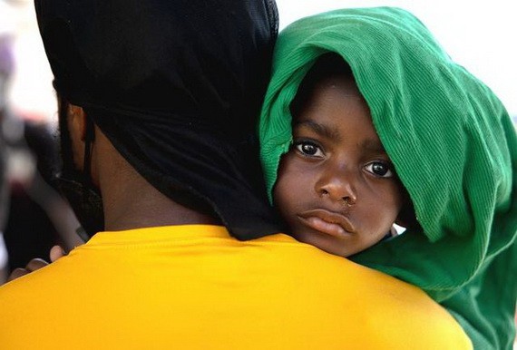 9月25日，在墨西哥阿庫尼亞城的移民收容所，一名來自海地的移民男孩和他的父親排隊向墨西哥移民官員遞交信息。（圖源：新華社）