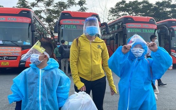 兩名身穿防護服的小孩在母親的陪同下準備上車返鄉。（圖源：文明）