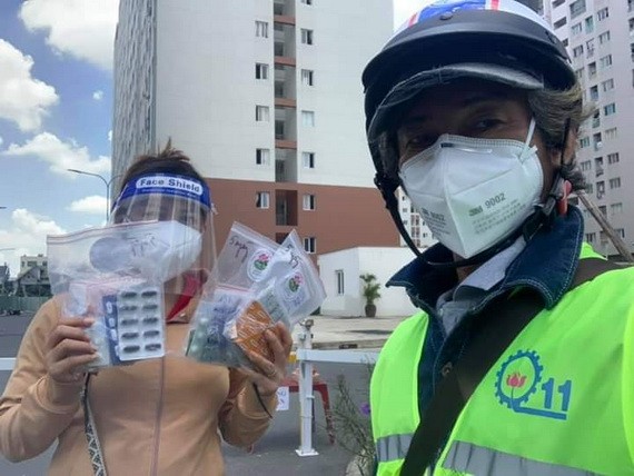 華人攝影家柯成智達(右)派發藥品給新冠患者。