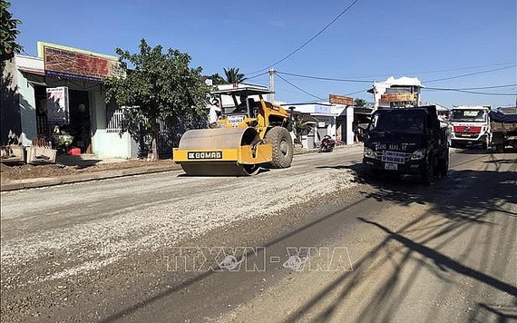 施工單位在擴寬改建途徑寧順省寧山縣仁山鄉公路路面。（圖：越通社）