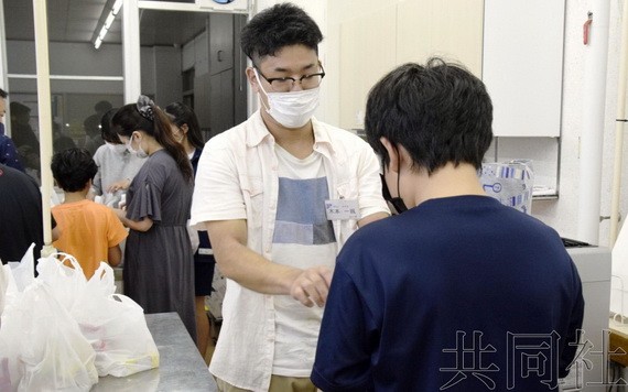 圖為NPO職員(左二)向貧困家庭子女發放食物。 9月攝於茨城縣筑波市。(圖:共同社)