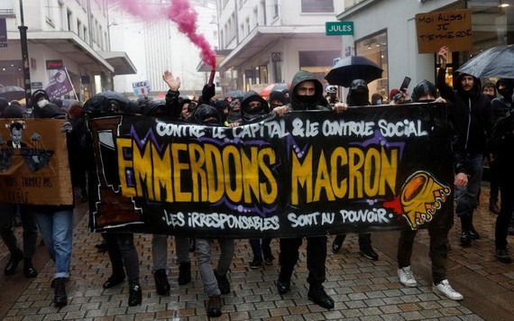 法國南特市民眾上周六帶著寫有斥責總統馬克龍的橫額，抗議政府推行「疫苗通行證」和收緊未接種新冠疫苗人士的出行限制。（圖：路透社）