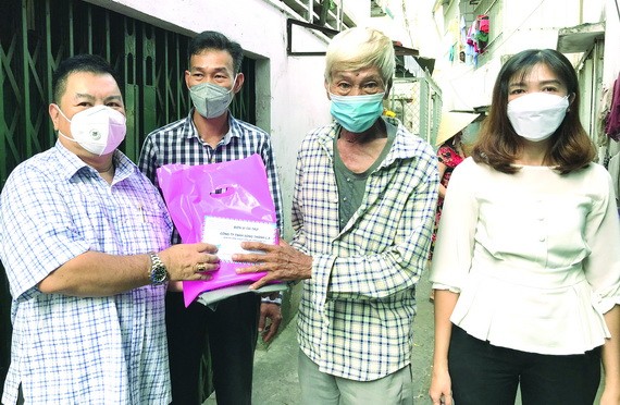 丁文森（左一）與坊領導向窮苦華人（右二）贈送禮物。