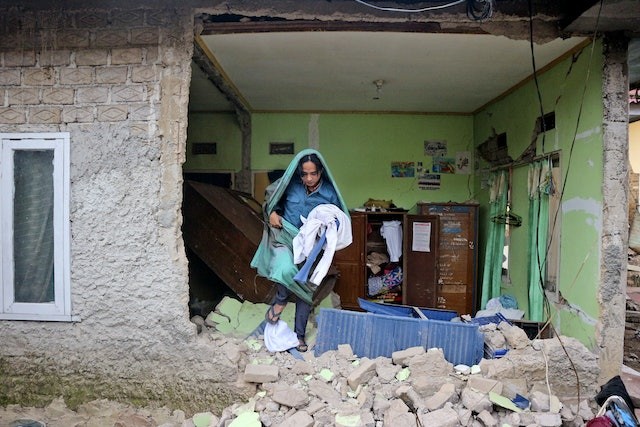 圖為2022年11月22日，印尼西爪哇省展玉一名地震災民返回受破壞的寓所拿取衣物。（圖：AP）