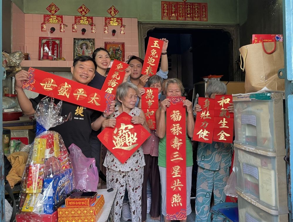 梁朝铭(后排右一)与众友向孤寡老人赠送挥春与春联。