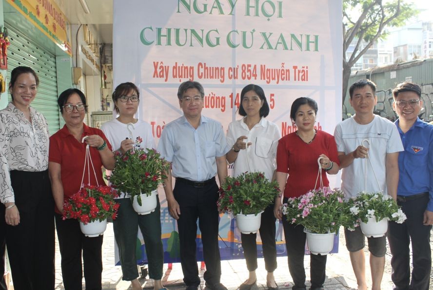 第五郡郡人委会副主席阮武春奇(中）向公寓居民赠送盆花。