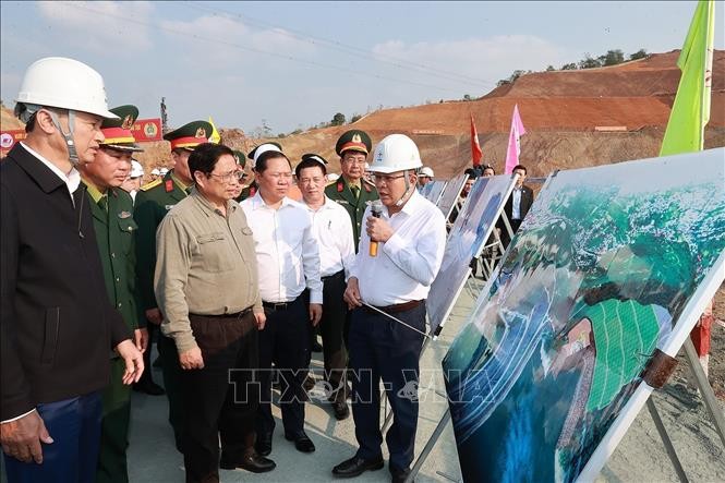 政府总理范明政在观看和聆听关于和平水电厂扩大工程的解说。(图:越通社)