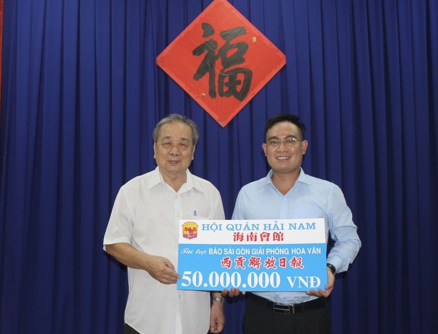 海南会馆常值副理事长孙盛强（左）把赞助赠报经费移交给本报编委文忠孝。