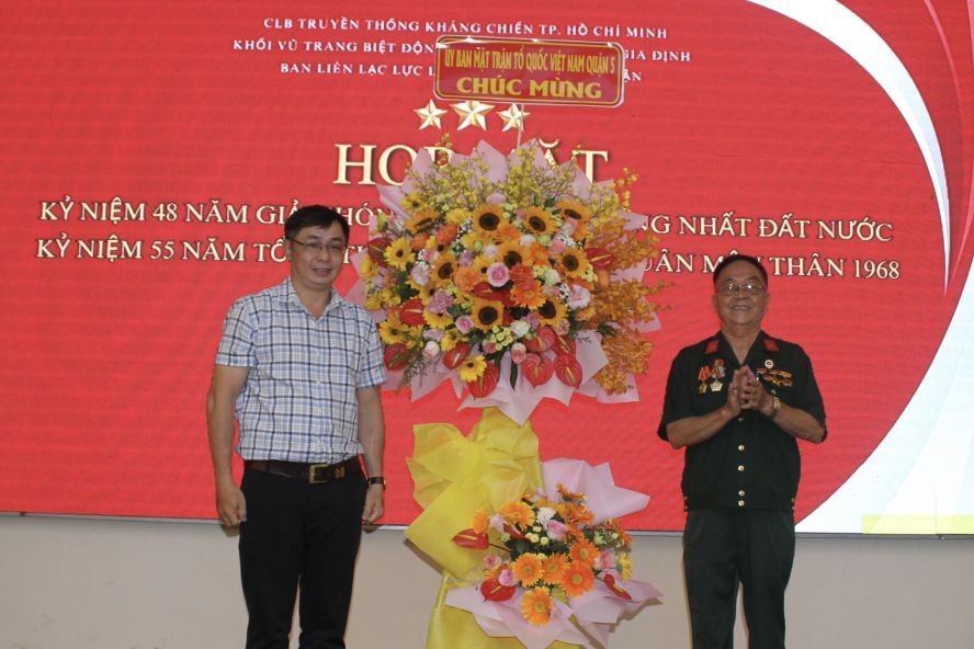 第五郡越南祖国阵线委员会副主席陈南德（左）向市华运武装力量联络组赠送花篮。