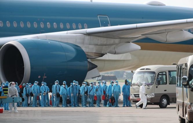 越南疫情爆发期间,以救援包机接回的海外公民在机场下机。(图:越通社)
