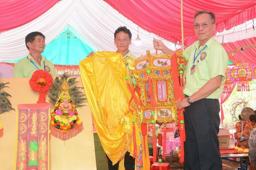 同奈省展邦县宝超城隍、观音庙理事会代表向吴俊文先生（中）移交“城隍爷袍”。