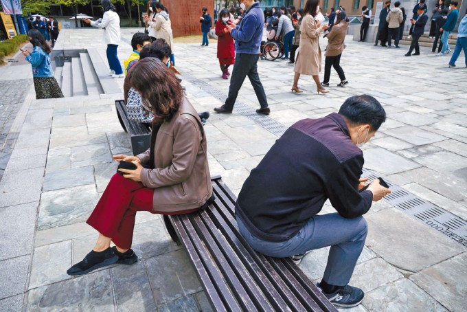 首尔上班族午膳时间在街上看手机。(图:互联网)