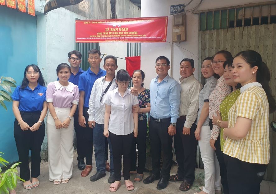 报社与地方领导同杨锦彪妻女（左五起）在屋子前合影。