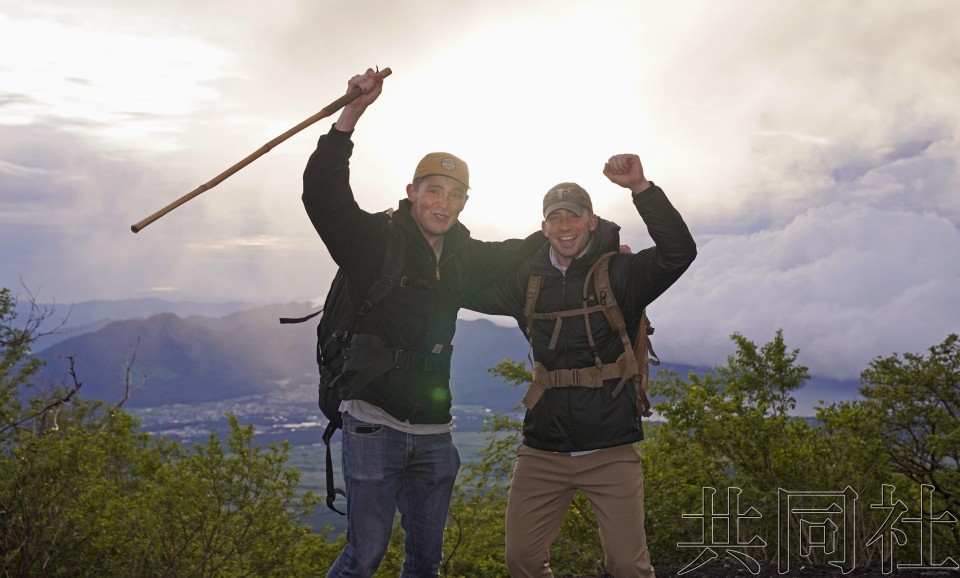 在迎来开山的富士山半山腰附近，外国登山客背向朝阳发出欢呼声。摄于7月1日。（图：共同社）