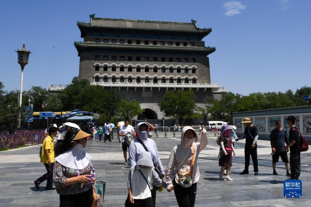 7月6日,游客走在北京市前门大街上。当日,北京市气象台7时升级发布高温红色预警信号,这也是今年北京市气象台发布的第二个高温红色预警。(图:新华社)