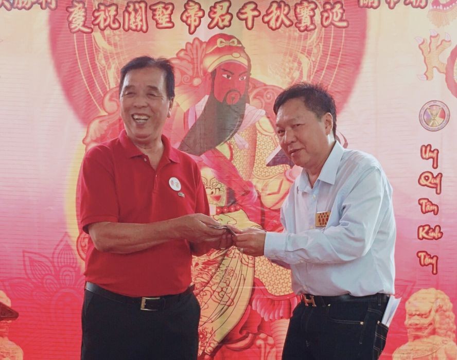 李东禧先生（左）代表旅美李武禧先生把1000美元移交给决胜村关帝庙理事长杨振明。