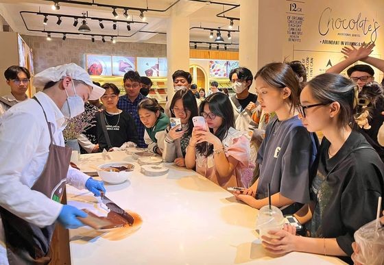 游客在西原科学研究院目睹观看艺人塑造巧克力的过程。