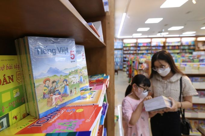 一名家长陪着女孩在书店里选购教科书。(图:青年)