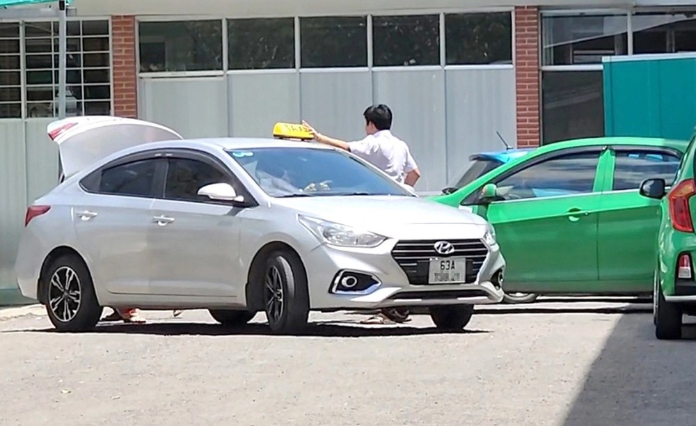 一名白色车牌司机接客上车后已拆掉了灯盒并准备将车驶出医院。