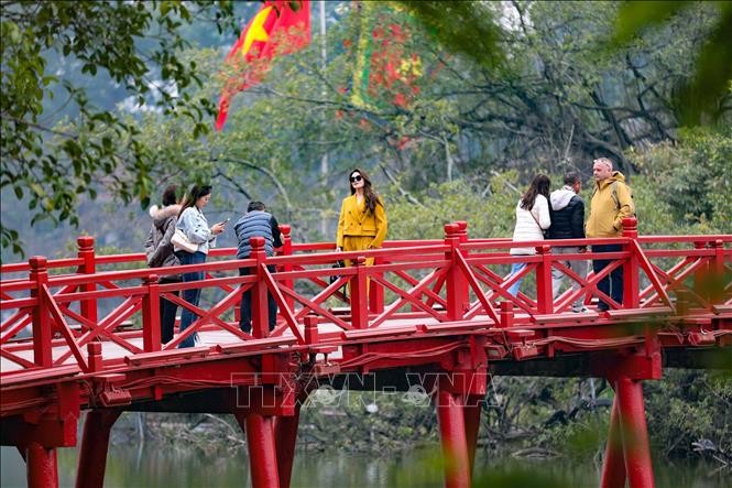 游客在河内市栖旭桥上观赏风景并拍照留念。(图:越通社)