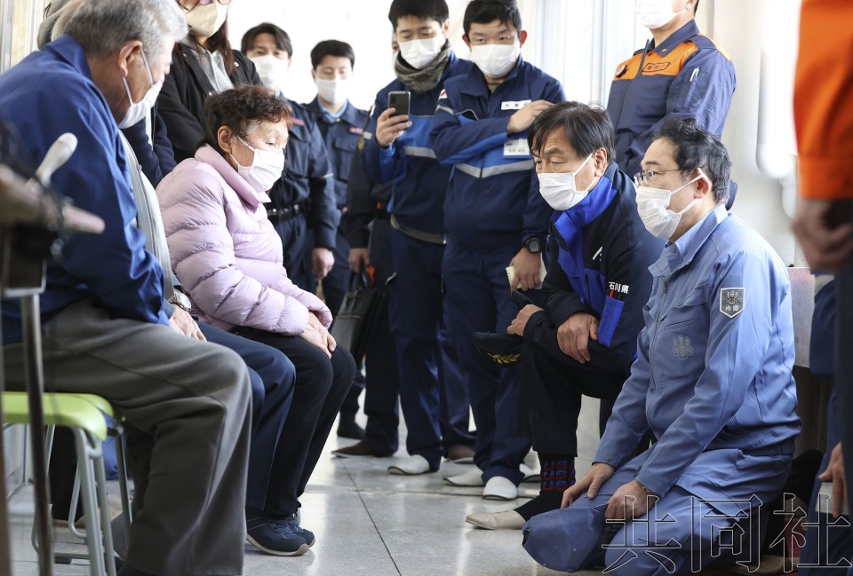1月14日下午,在设有避难所的石川县珠洲市一所中学内与灾民交谈的日本首相岸田文雄(右一)(图:共同社)
