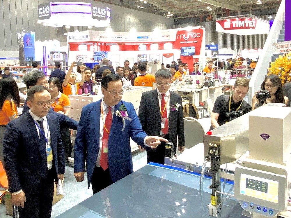 越南纺织协会主席武德江（左二）参观展摊。