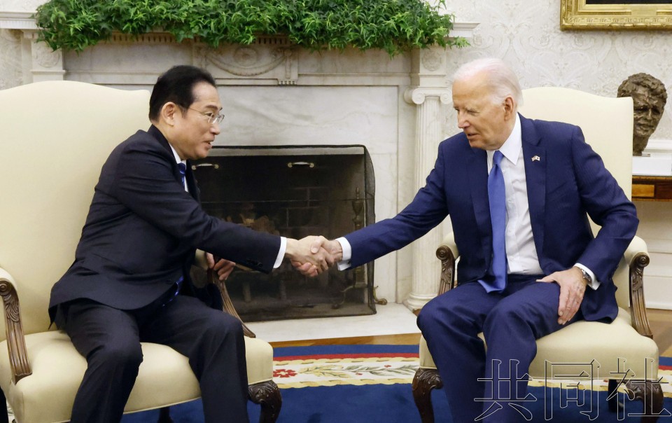 日本首相岸田文雄(左)与美国总统拜登在会谈上握手。(图:共同社)
