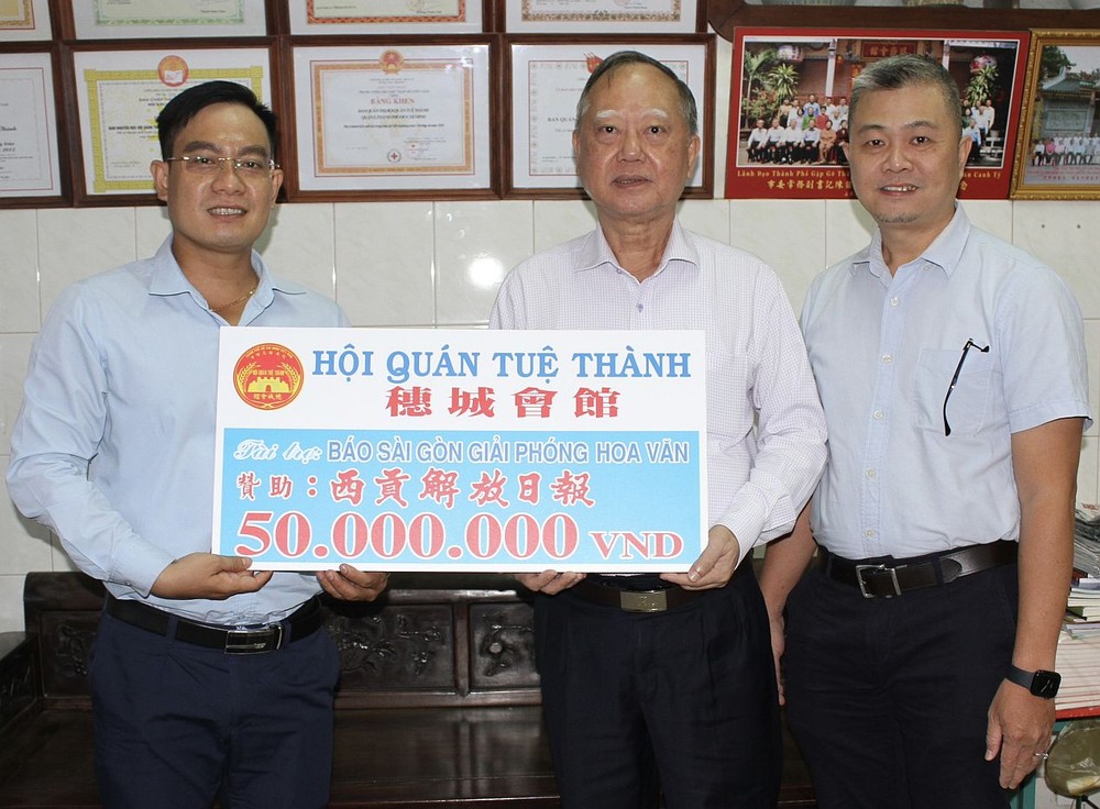 穗城会馆理事长卢耀南和理事梁锦权向本报编委文忠孝移交5000万元赠报经费。