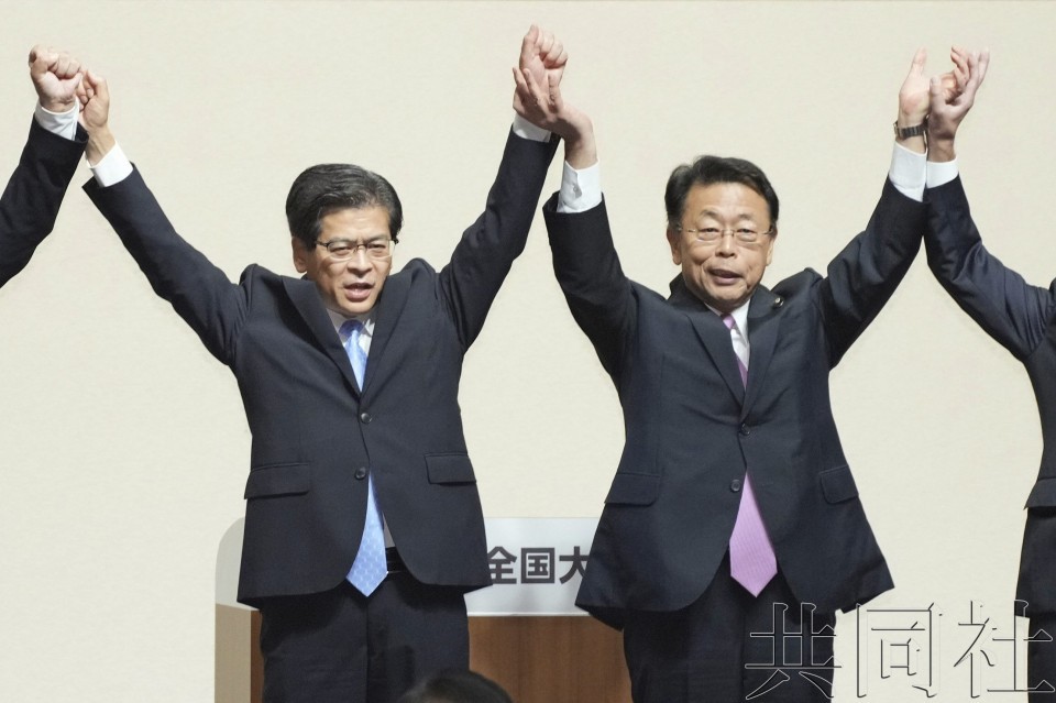 日本公明党新党首石井启一(左)与新干事长西田实仁在党大会上举臂回应掌声。(图:共同社)