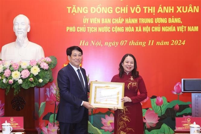国家主席梁强代表党和国家领导人郑重向武氏映春授予30年党龄纪念章。(图:越通社)