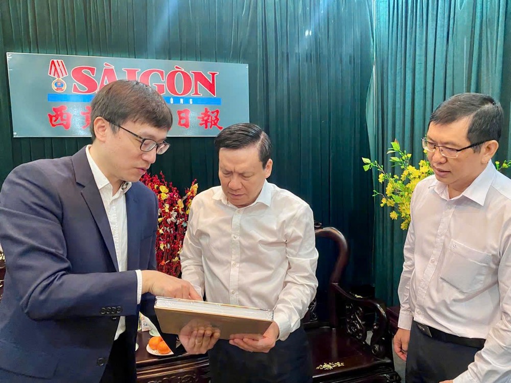 《中新社》香港分社总编辑曾嘉(左一)向华文《西贡解放日报》主编阮玉英介绍该社的纪念册。 K3.jpg