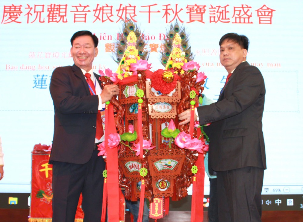 该庙副理事长叶其达（左）向邓奕敏先生移交“莲花宝灯”。