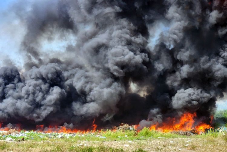 图为3月13日上午，平新郡一块数十公顷空地上的垃圾场冒出滚滚浓烟，火势迅猛，威胁到周围的停车场。（图：孟玲）