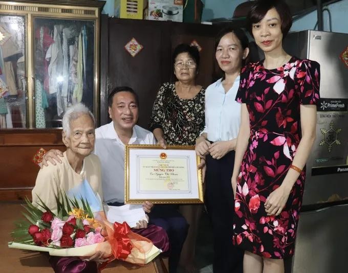 市人民议会副主席范成坚(左二)与代表团向古芝县高龄人模范阮氏款(左一)祝寿并赠送贺寿状。