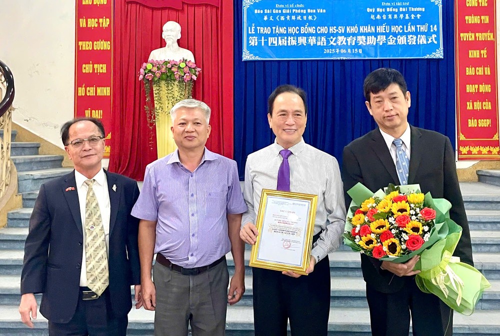 华文《西贡解放日报》编委黎曰孟雄(左二)向台商奖学基金会颁发感谢状与鲜花。 trao-bong-hoc-2.jpg