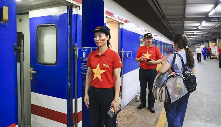 穿着红衫与金星制服的铁路员工正为统一列车乘客服务。(图:越通社)