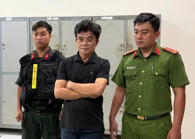 嫌犯武成心(中)在听取执法警员宣读拘捕令。(图:警方提供)