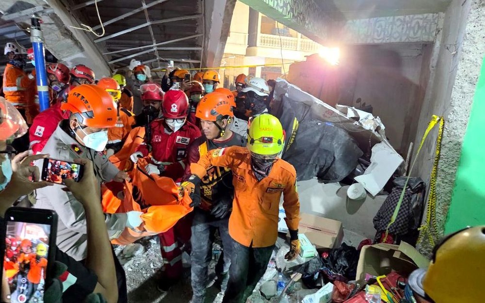 10月1日，救援人员在印度尼西亚东爪哇省诗都阿佐县建筑倒塌现场搬运遇难者遗体。（图：新华社）