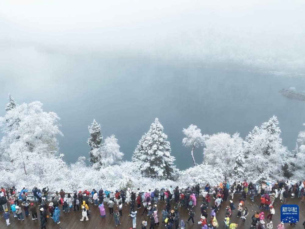 图为游客在九寨沟长海欣赏雪景（10月24日摄，无人机照片）。 （图：新华社）