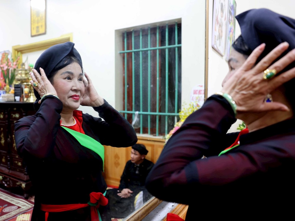 女歌手整理乌鸦嘴头巾，为更曲表演做准备。图自越通社