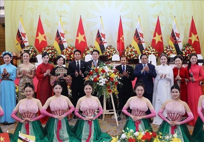 越南国家主席梁强、政府总理范明政与哈桑纳尔·博尔基亚苏丹和越南歌舞团成员合影。（图：越通社）