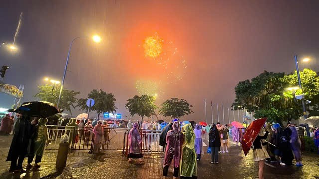 人潮“冒着雨”观看烟花。