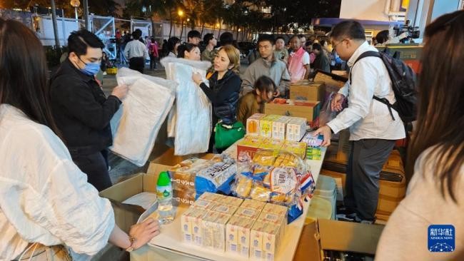 11月26日，受火灾影响的居民在跨部门援助站领取救援物资。