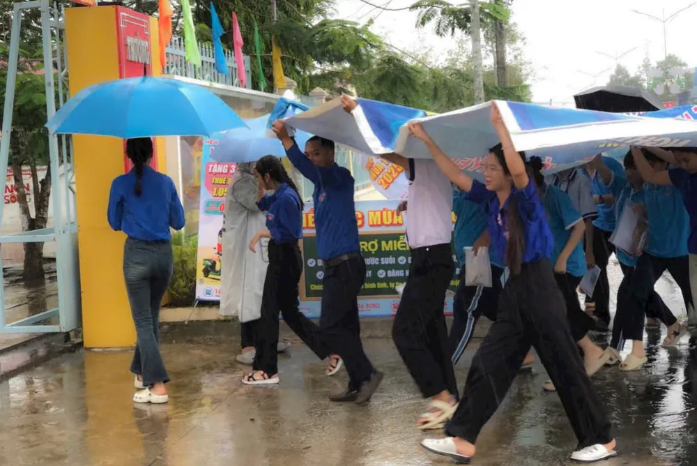 Các tình nguyện viên dùng bạt lớn che chắn cho thí sinh khỏi ướt 112c9eb4dc6c6b32327d.jpg