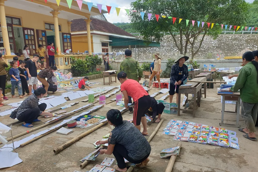 Người dân cùng thầy cô, học sinh trường Tiểu học Châu Hạnh 2 tranh thủ trời nắng phơi sách vở bị ướt