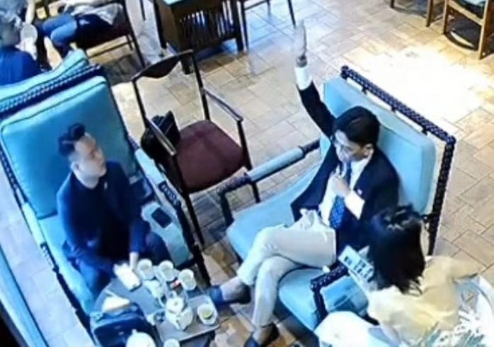 穿西装的男子举手示意并喊着“够了，够了，够了”。